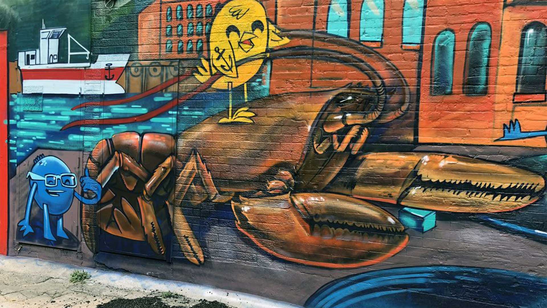 Graffiti on a wall in an alleyway depicting a lobster and a yellow bird on top of it