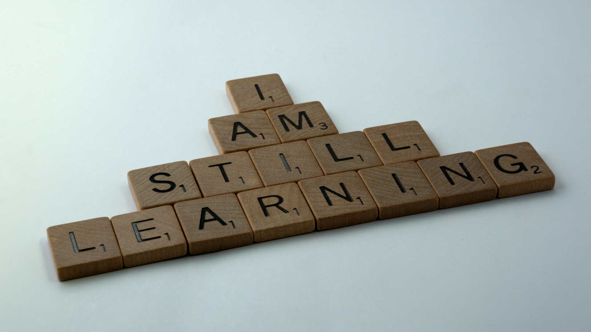 Scrabble tiles spelling out "I am still learning"