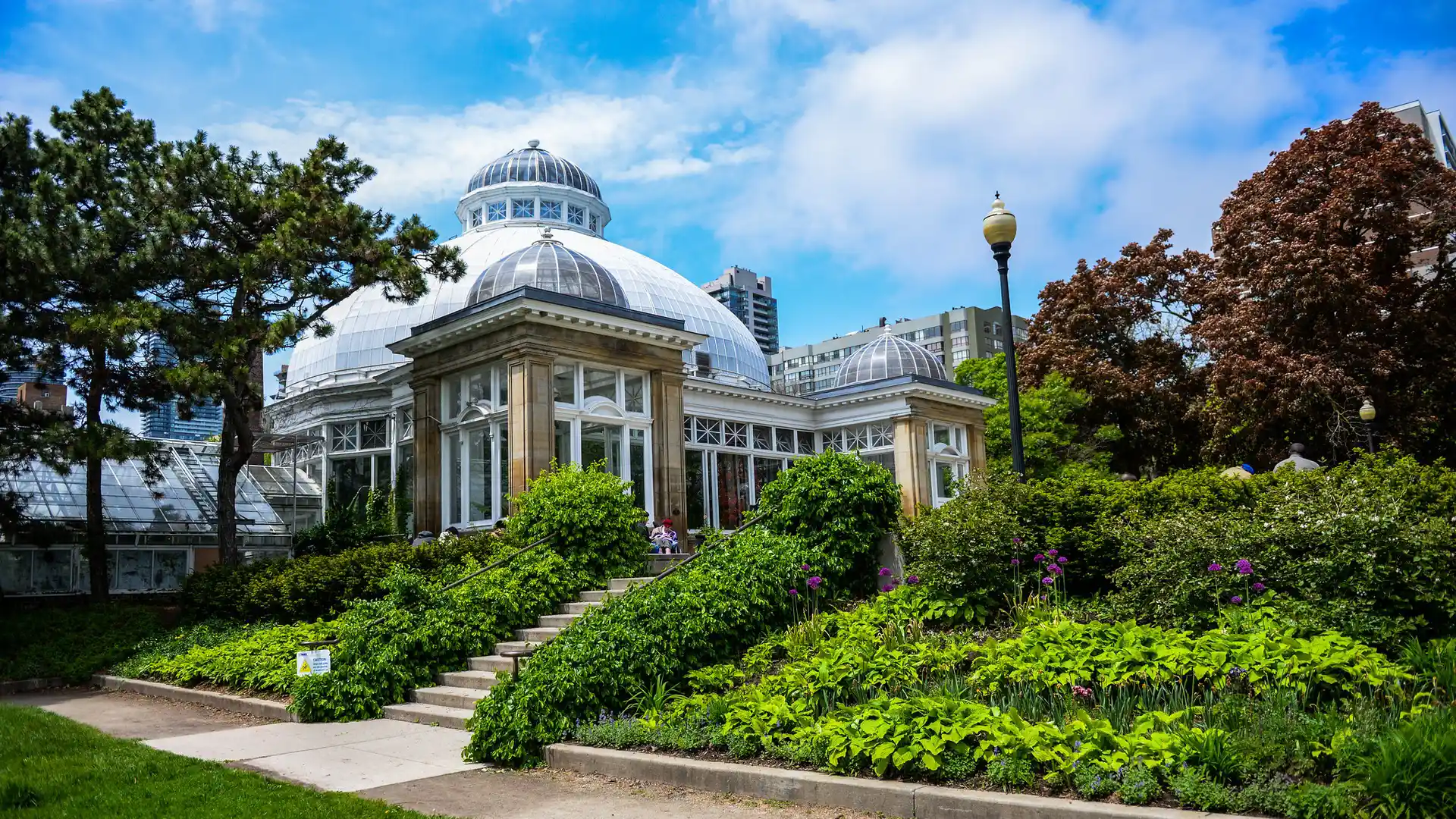 The Allan Gardens Conservatory glass dome and surrounding gardens in Toronto on a summer day