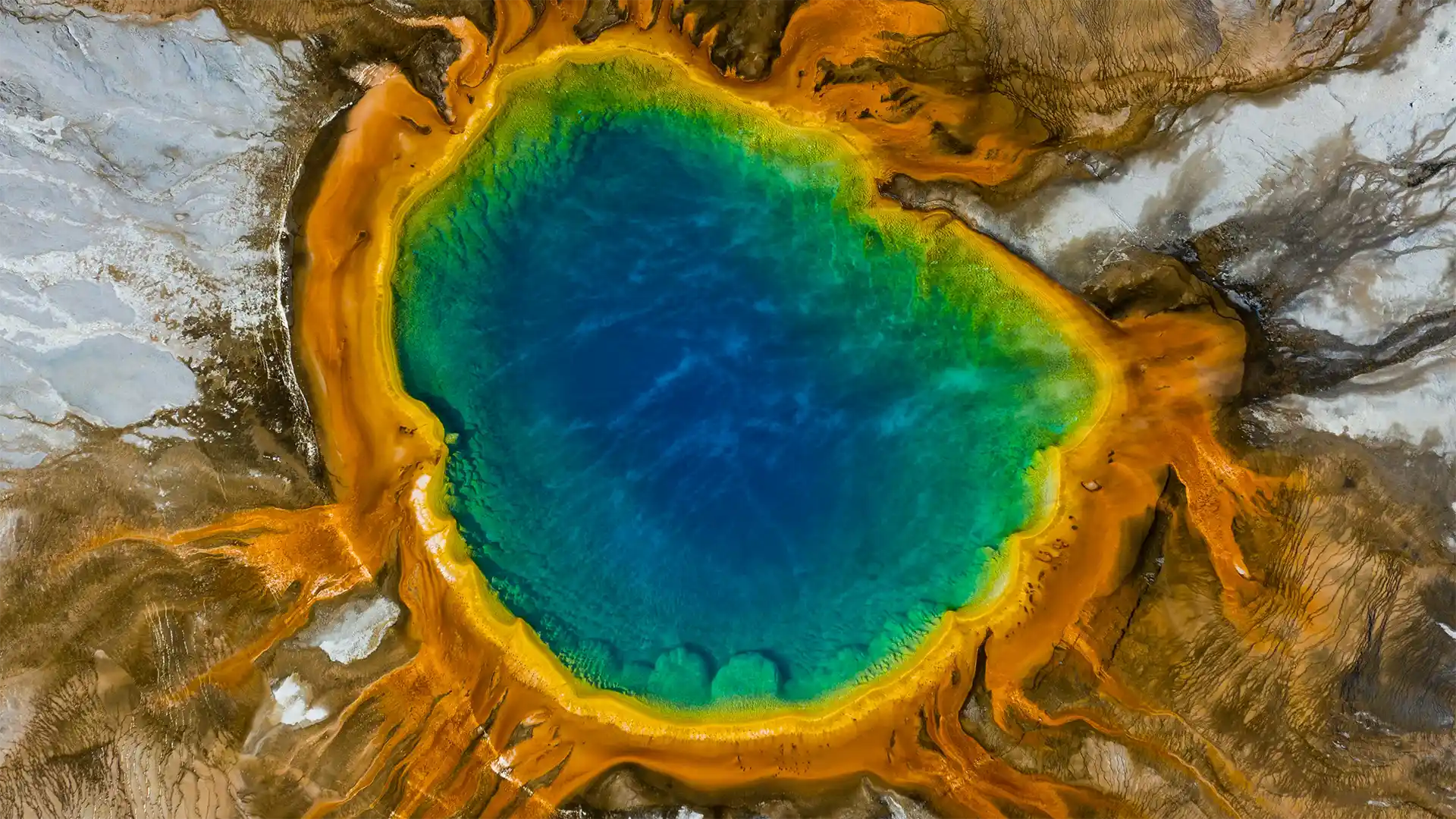 aerial photo of lake in Yellowstone National Park with various colours around the outer shores.
